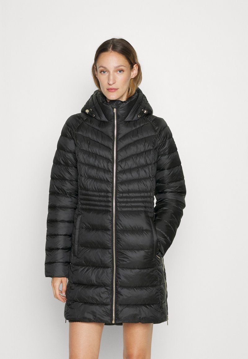Zwarte pufferjas met een gewatteerd patroon, ritssluiting aan de voorkant, zijzakken en een afneembare capuchon. Glad materiaal met glanzende accenten.