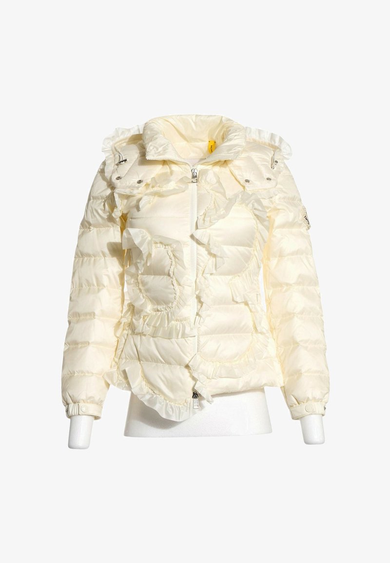 Doudoune couleur crème avec détails à volants, fermeture éclair à l’avant, col montant et poignets élastiques sur un torse partiel de mannequin.