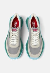 Sneaker grigie e teal con una parte superiore in mesh testurizzato, lacci bianchi e una soletta rossa, caratterizzate da una spessa suola in gomma blu per una buona aderenza.