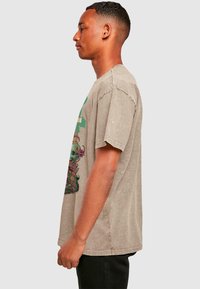 Gray cotton T-shirt featuring a colorful floral skull graphic. Short sleeves and a relaxed fit. Visible seam detailing and slightly faded texture.