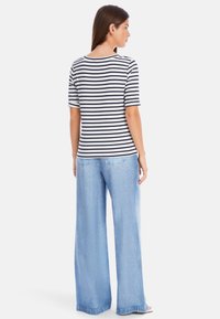 Striped navy and white short-sleeve top paired with light blue wide-leg jeans, featuring a relaxed fit and a soft texture.