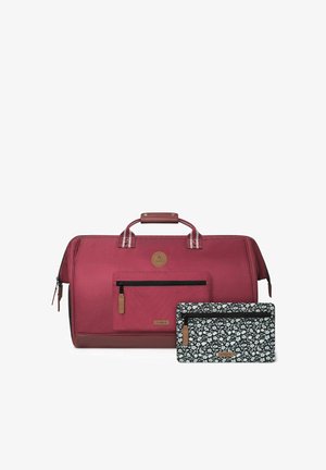Sac de sport en tissu rouge avec une poche avant, des accents en cuir cousus et une pochette florale noire. Les deux présentent des fermetures à glissière et des logos de marque.