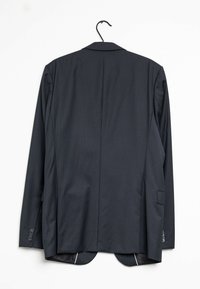 Giacca da abito a righe grigio scuro appesa a un gancio. Presenta un rever a scarico, due tasche frontali e uno schienale ventilato con accenti bianchi.