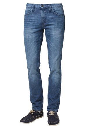 Blauwe slim-fit jeans voor heren met voorzakken en riemlussen, gecombineerd met marineblauwe casual veterschoenen.