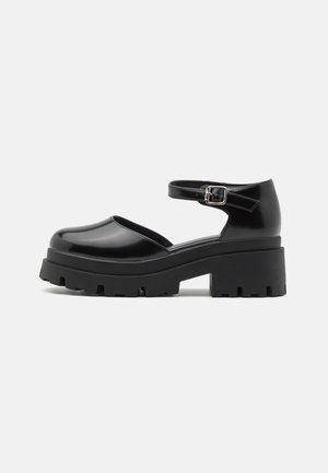 Sort platform Mary Jane-sko med chunky sål og ankremspænde, glat finish, set fra siden på ensfarvet baggrund.