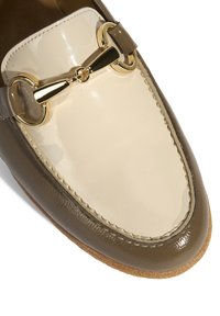 Loafer met een tweekleurige bovenkant in glanzend beige en olijfgroen leer, met een goudkleurig paardenbitdetail en een gestructureerde, lichtbruine zool.