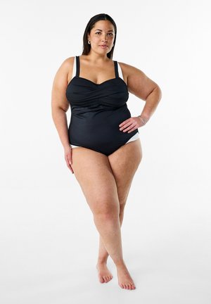 Costume intero nero con arricciature sul corpetto, spalline regolabili e dettagli bianchi sui fianchi. Tessuto liscio e elastico.