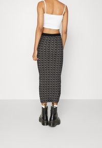 Midilång svart kjol med ett vitt vågmönster, tillsammans med svarta kängor. En figursydd vit crop top fulländar outfiten.