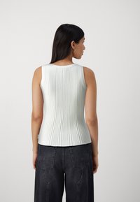 Light blue, ribbed sleeveless top with a rounded neckline. Soft texture, fitted silhouette, and slightly flared hem detail.