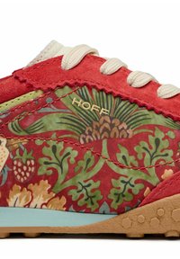 Baskets en tissu rouge et vert présentant des motifs floraux, avec des lacets blancs et une semelle en caoutchouc bleu clair avec des accents texturés. Logo "HOFF" visible.