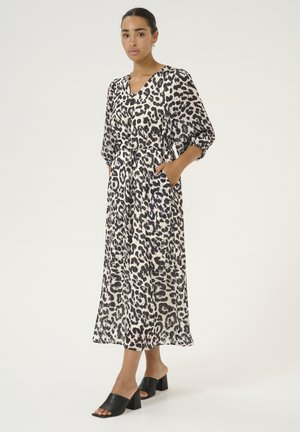 Leopard print maxi dress with a V-neckline, long sleeves, and pockets, made of lightweight fabric; worn with black block-heeled mules.