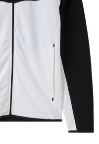 Giacca a zip in bianco e nero. Tessuto morbido e spazzolato con colori a contrasto. Presenta tasche con zip nere e un design aderente.
