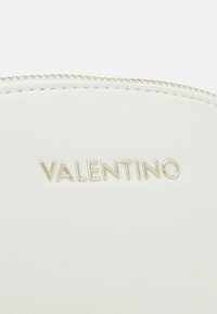 Vit läderpung med en slät yta, utrustad med en guldfärgad dragkedja och präglad "VALENTINO"-logotyp i modern stil.