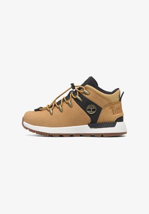 Brązowe zamszowe buty typu mid-top z czarnymi akcentami, solidną podeszwą, mosiężnymi elementami oraz detalem logo po zewnętrznej stronie; posiadają wzmocniony język.