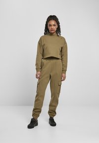 Olivengrønn cropped sweatshirt med høy hals, kombinert med matchende cargo joggers som har sidelommer, teksturert stoff og elastiske mansjetter.