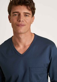 Marineblauwe V-hals t-shirt van zachte stof, met een borstzak en korte mouwen, met een gladde textuur en een relaxte pasvorm.