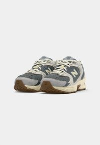 Gray and cream running shoes with mesh and suede materials, prominent cushioning, classic lacing, and gum rubber outsole. Notable logo on the side.