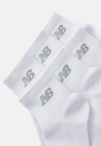 Bijele pamučne čarape s rebrastom teksturom. Imaju suptilan sivi New Balance logo na rubu. Set od tri para.