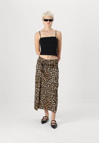 Melna īsa tanku krekls, leopardu raksta apvilkšanas svārki un norādījuma melnas kurpes. Apģērbs ir ar elegantu, minimālistisku dizainu un gludām tekstūrām.