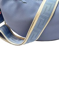 Ronde, lichtblauwe leren tas met een gestructureerde afwerking; voorzien van een gestreepte blauw en crèmekleurige schouderband.