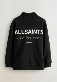 Črna pulover s visokim ovratnikom, ki ima velike bele napise: "ALLSAINTS," japonske znakove in "LONDON." Mehka tkanina, sproščen kroj.