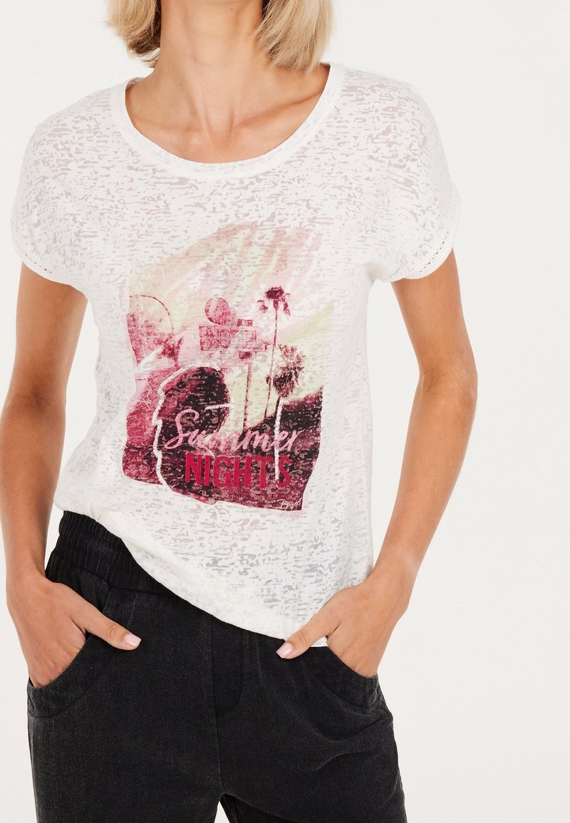 Vit kortärmad t-shirt med en något texturerad tyg, med en färgglad grafiktryck som läser "Sommarkvällar" i fetstil.