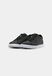 Zwarte synthetische sneakers met platte veters, witte rubberen zolen en subtiele logomarkeringen. Gladde textuur, ronde neus design.