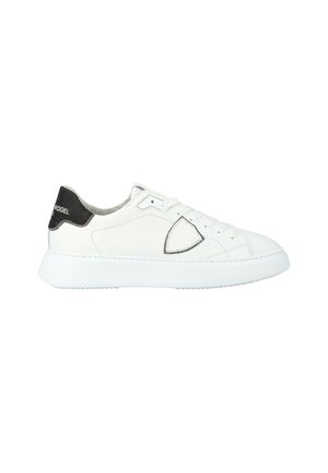 Baskets blanches avec un dessus en cuir lisse, bout arrondi et une semelle blanche texturée. Présentent un accent de talon noir contrastant.