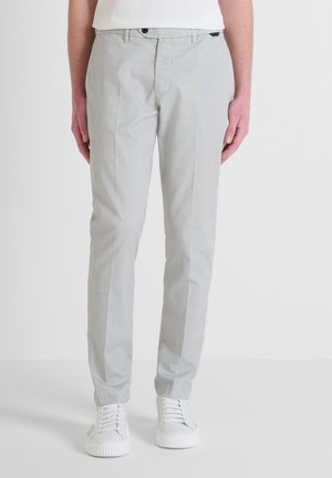 Pantalones gris claro con un patrón de textura fina, ajuste tapered y cinturilla clásica, combinados con zapatillas blancas.