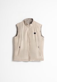 Chaleco sin mangas color beige, hecho de tejido suave, con cuello alto, cierre frontal y dos bolsillos laterales. Logo sutil en la zona del pecho.