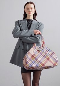 Laukku duffel ruudullisena pastelliväreissä ja kiiltävällä pinnalla; varustettu tukevilla kahvoilla ja kiiltävällä metalliyksityiskohdalla ylhäällä.