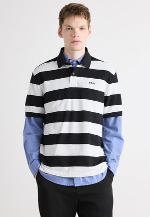 Black and white striped polo shirt with a solid black collar, featuring a logo on the chest, layered over a light blue button-up shirt.