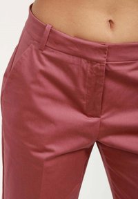 Rosa skräddarsydda byxor i slätt tyg, med sidofickor och en strukturerad midja utan synliga knäppningar.