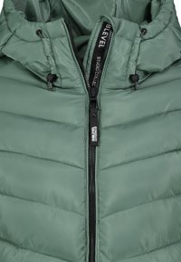Groene pufferjas met capuchon, voorzien van diagonale stiksels, zwarte ritssluiting en merknaam op de rits en voering.
