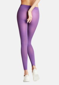 Paarse legging met een gladde, rekbare textuur, voorzien van een hoge tailleband en een enkellange pasvorm, gecombineerd met witte sneakers.