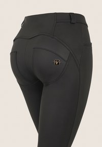 Mustat korkeavyötäröiset legginsit, joissa on sileä ja joustava pinta. Niissä on viistot takataskut ja pieni kullanvärinen logodetalji.