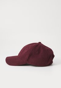 Casquette de baseball en velours côtelé bordeaux avec un bord incurvé, en tissu texturé, design à six panneaux et œillets de ventilation sur le dessus.