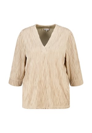 Blouse beige texturée avec manches 3/4 et encolure en V, présentant un motif gaufré ondulé.