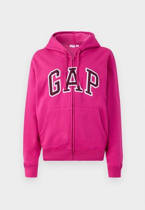 Haut zippé rose vif avec poches avant, capuche à cordon de serrage et grand logo GAP blanc et noir sur la poitrine.