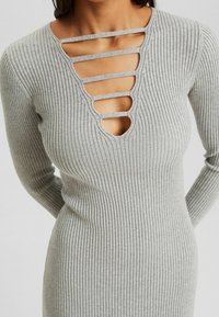Graues geripptes Strickkleid mit tiefem V-Ausschnitt und horizontalen Ausschnitten, langen Ärmeln und einer enganliegenden Silhouette. Weicher Stoff mit leichtem Stretch.