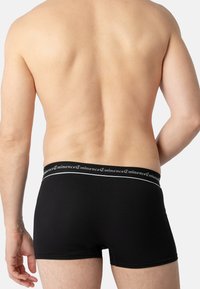Boxer-chaussettes en coton noir avec une ceinture élastique douce ornée de texte blanc. Le design est simple et ajusté, offrant une couverture minimale.
