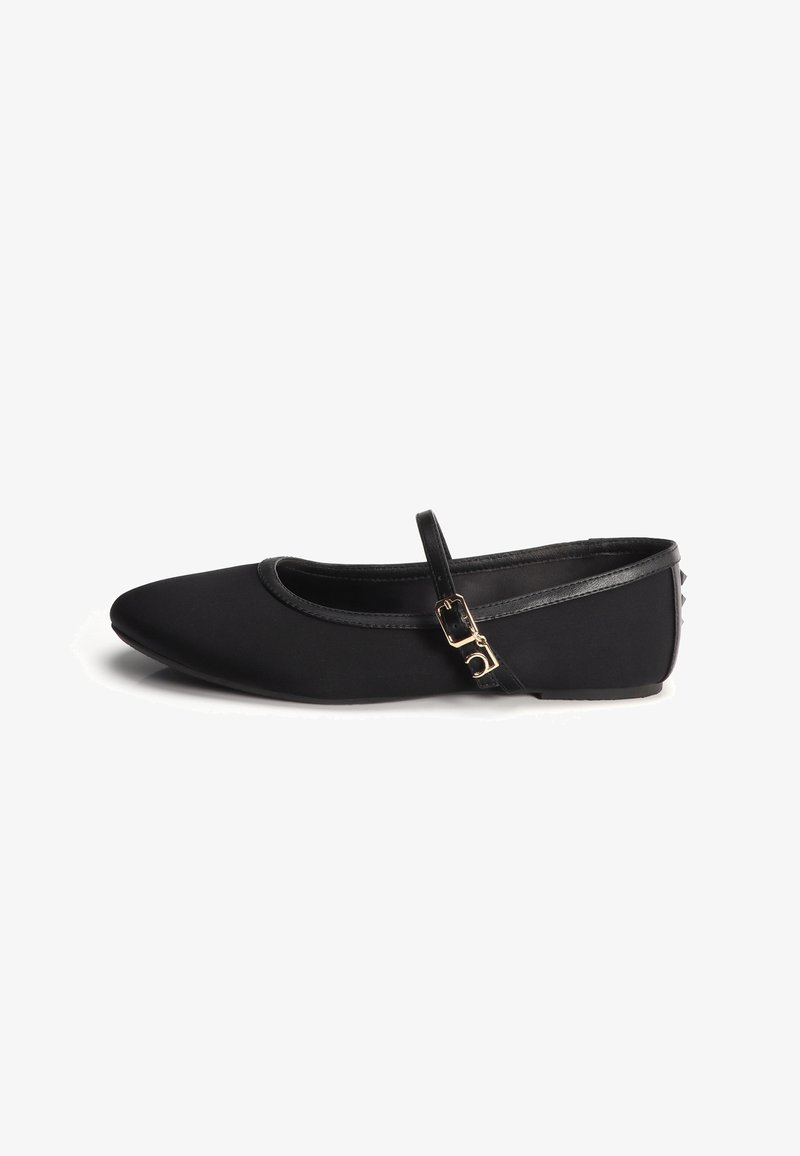 Chaussure ballerine plate noire à bout pointu, fine bride traversant le dessus maintenue par une petite boucle dorée, avec des détails de petits clous subtils sur le talon.