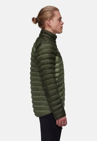 Grön isolerad jacka med horisontell pufferdesign, hög krage och dragkedjefickor. Slät textur med lätt material.