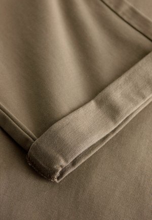 Beige Baumwollstoff, gefaltet mit glatter Textur, einer klaren Kante und einem subtilen Rippenmuster; weiches und flexibles Aussehen.