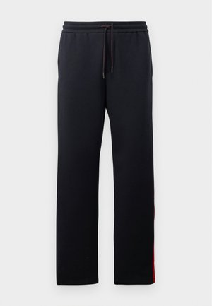 Pantaloni sportivi neri con vita regolabile, gambe affusolate e strisce rosse lungo i lati. Tessuto morbido e elastico con una superficie liscia.