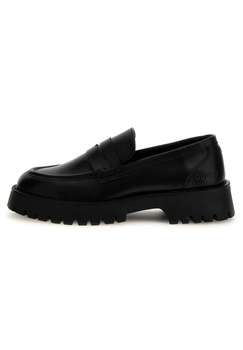 Black leather loafers with a thick, ridged sole. Features a stitched moccasin toe and a frontal strap. Branding is visible on the heel.
