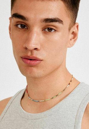 Värvikas helmestega kaelakee, mis koosneb erinevatest väikestest ümaratest helmestest, sisaldades erinevaid värve nagu punane, sinine, roheline ja kuldsed aktsendid.