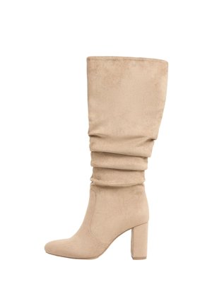 Beige ruskind midtkalv slouch-støvle med rund tå og blokhæl, vist fra siden på hvid baggrund.
