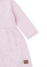 Vestido para bebé de punto color rosa claro con mangas largas y un patrón de diamantes en la falda, con una pequeña etiqueta cuadrada marrón en la parte inferior.