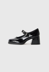 Chaussures Mary Jane en cuir verni noir avec un bout rond, une bride à boucle réglable et un design à talon bloc.